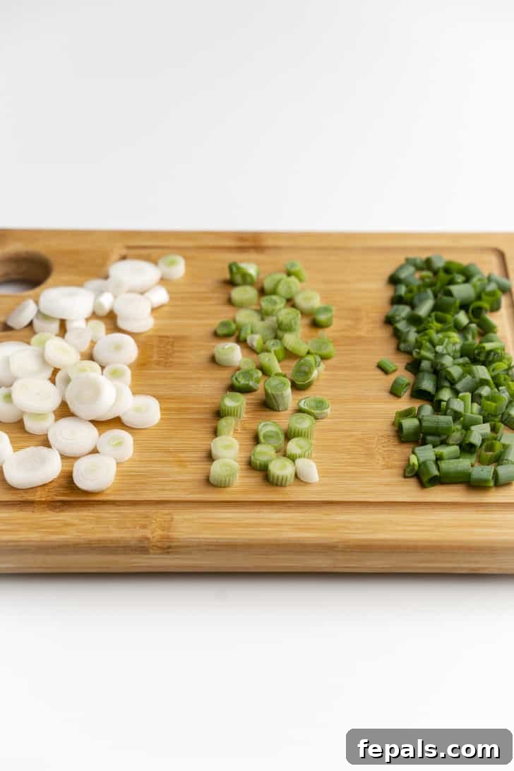 A collection of evenly sliced green onions scattered on a wooden cutting board