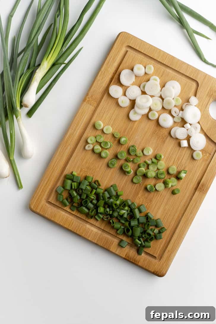 Assortment of perfectly sliced green onions arranged on a wooden cutting board, ready for use