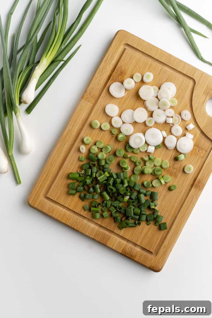 Close-up photograph of neatly and evenly sliced green onions on a wooden cutting board
