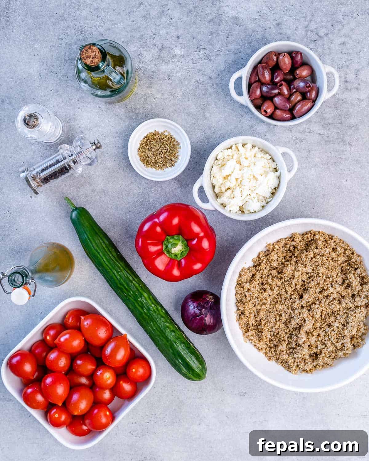 Healthy Greek Quinoa Salad With Feta Arrangement of fresh ingredients for Greek quinoa salad: kalamata olives, feta cheese, oregano, olive oil, salt, pepper, cucumber, bell pepper, red onion, cooked quinoa, cherry tomatoes, and red wine vinaigrette