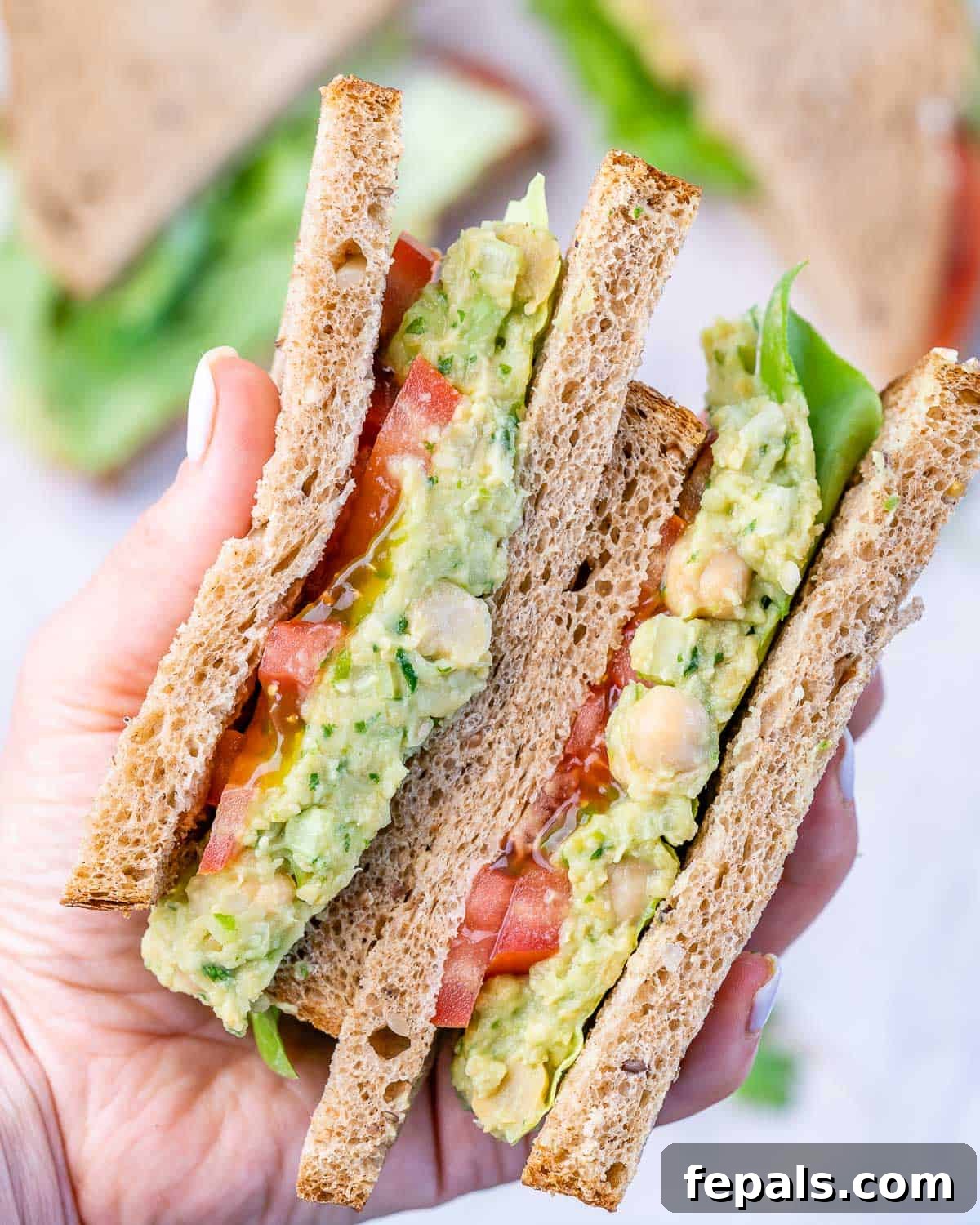 Chickpea Avocado Sandwich Top-down view of an open chickpea avocado sandwich with tomato slices and lettuce on whole wheat bread.