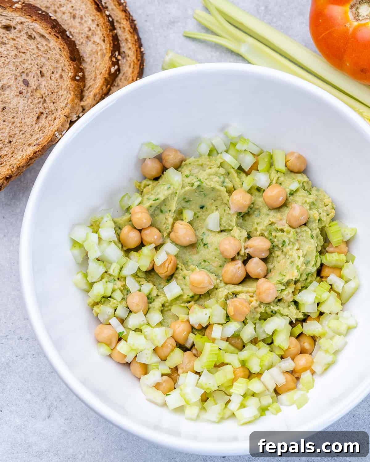Avocado and Chickpea Sandwich Recipe A bowl containing the mashed avocado and chickpea mixture, with whole chickpeas and chopped celery stirred in.