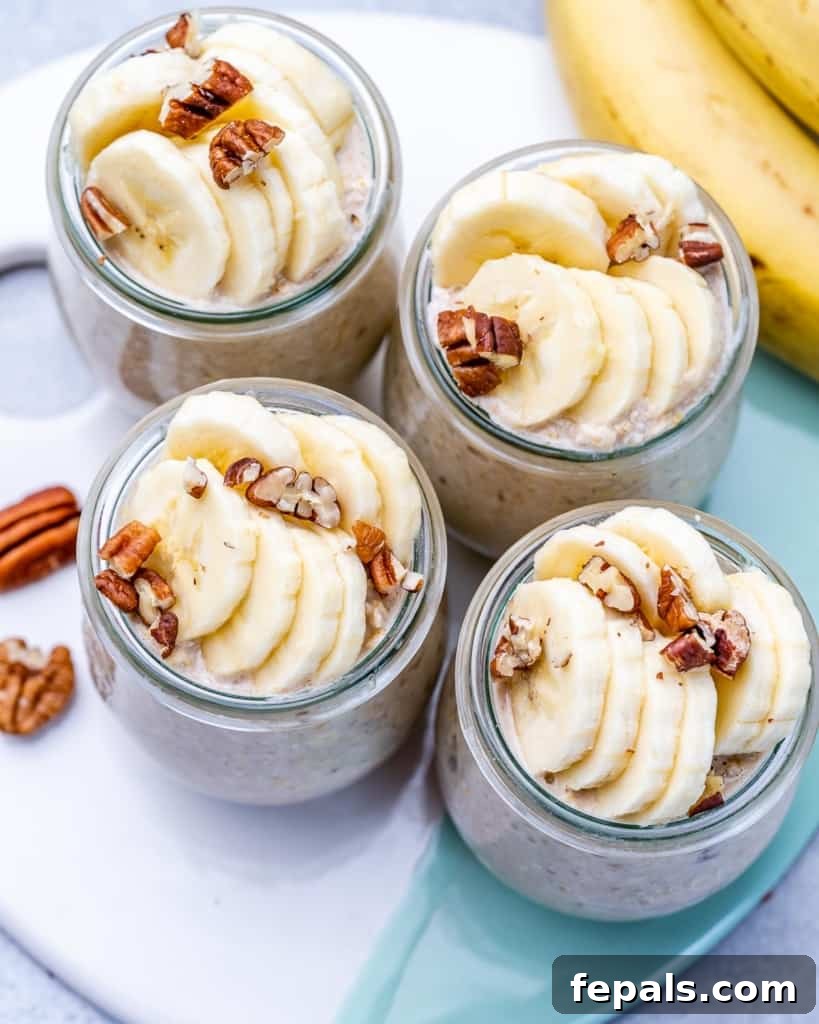 No-Bake Banana Bread Oats 3 Close-up shot of four beautifully arranged glass jars filled with creamy overnight oats, meticulously garnished with perfectly sliced bananas and finely chopped pecans, showcasing their delicious texture and inviting presentation.
