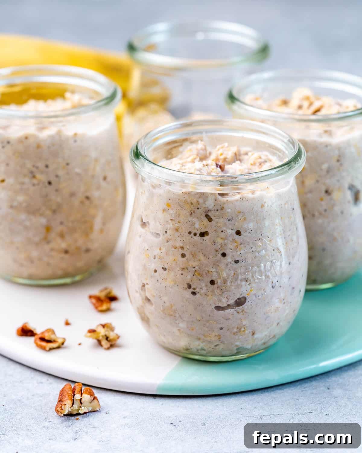 No-Bake Banana Bread Oats 6 The combined overnight oats mixture being carefully poured into four clean, individual glass jars with lids, signifying preparation for refrigeration.