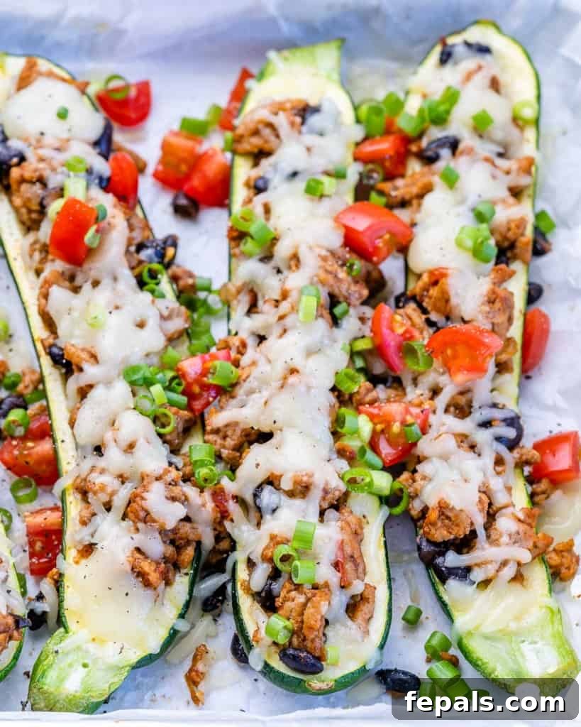 Top view of delicious Taco Stuffed Zucchini Boats garnished with melted cheese and fresh chopped tomatoes.