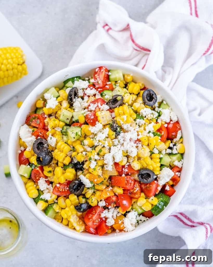 Sunshine Corn Salad 2 Overhead shot of summer corn salad in a white bowl surrounded by a cloth and ingredients on a table.
