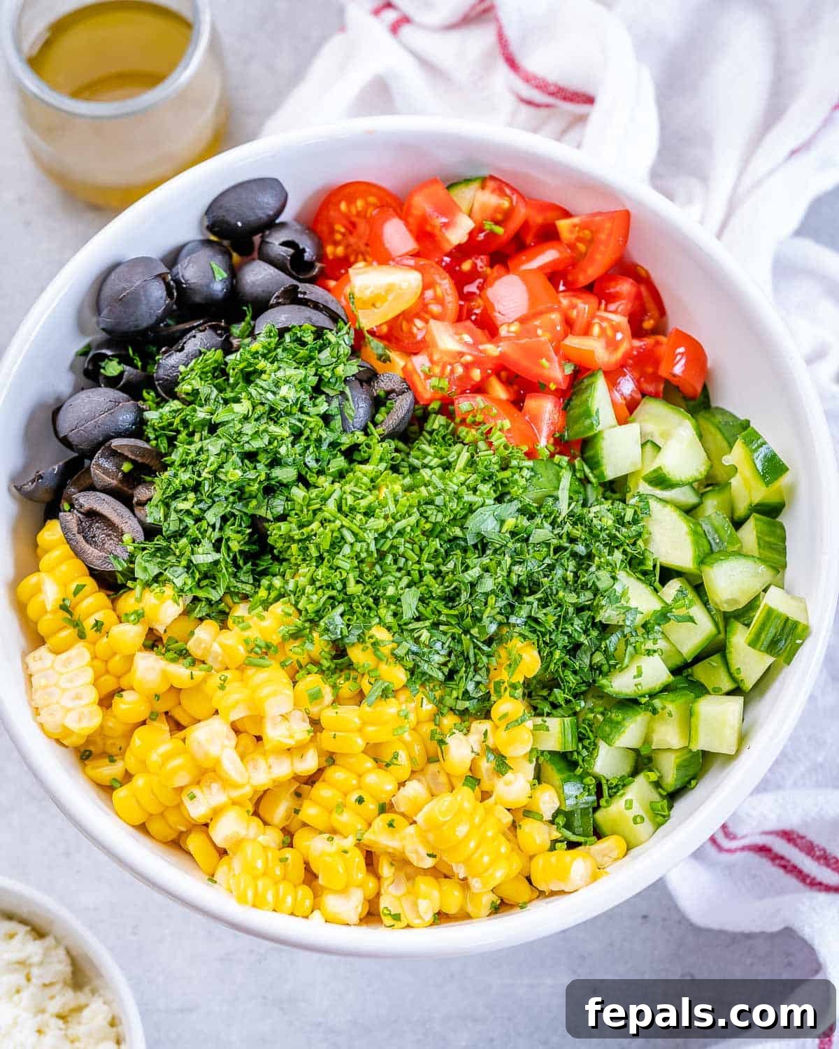 Sunshine Corn Salad 6 Freshly chopped vegetables and feta being added to a bowl with corn.