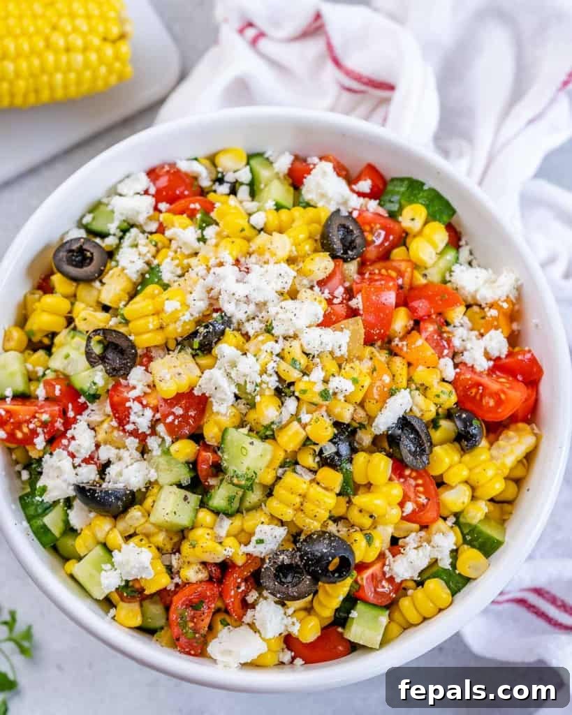 Sunshine Corn Salad 7 Overhead shot of summer corn salad in a white bowl surrounded by a cloth and ingredients on a table.
