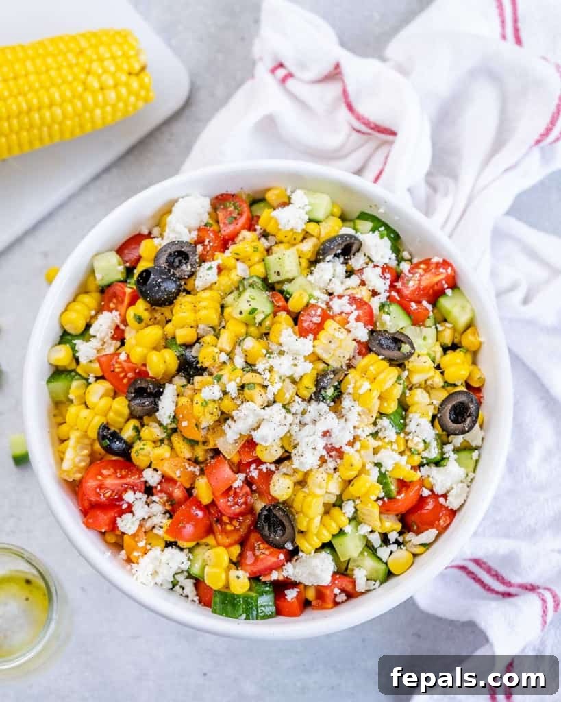 Sunshine Corn Salad 8 Overhead shot of summer corn salad in a white bowl surrounded by a cloth and ingredients on a table.