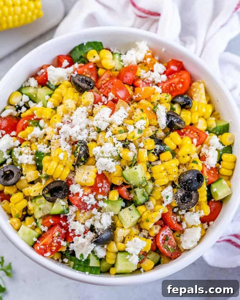 Sunshine Corn Salad 9 Overhead shot of summer corn salad in a white bowl surrounded by a cloth and ingredients on a table.
