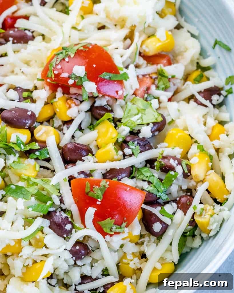 Golden Chicken with Fiesta Rice Core 6 A close-up of a bowl with taco filling ingredients being stirred together: cheese, black beans, corn, tomatoes, and cilantro.