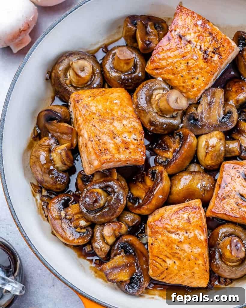 Top-down view of beautifully glazed honey balsamic salmon fillets nestled among sautéed mushrooms in a skillet, ready to serve.