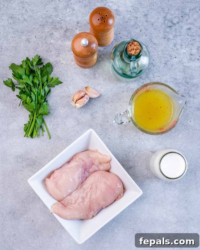 Ultimate Creamy Garlic Chicken Skillet 4 A flat lay photograph showcasing all the fresh ingredients needed to prepare a creamy garlic chicken skillet meal: chicken breasts, garlic, olive oil, heavy cream, chicken broth, parsley, salt, and pepper.