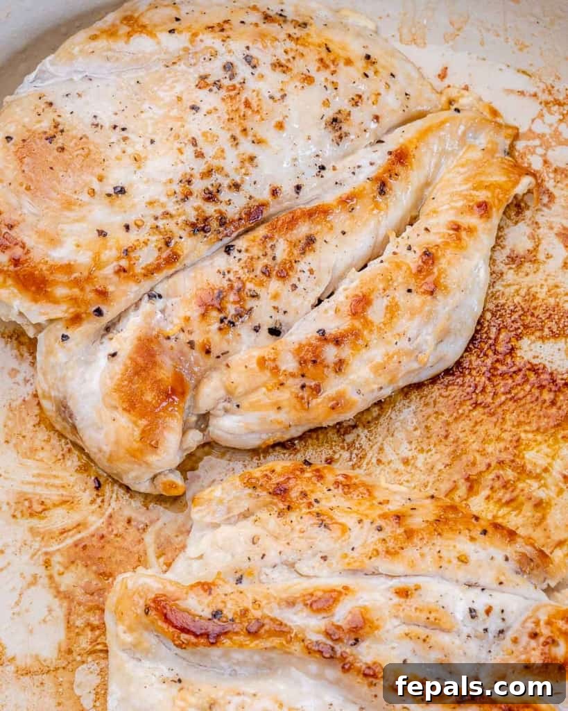 Ultimate Creamy Garlic Chicken Skillet 5 Two chicken breasts sizzling and browning in a large, hot skillet, releasing delicious aromas as they cook to perfection.