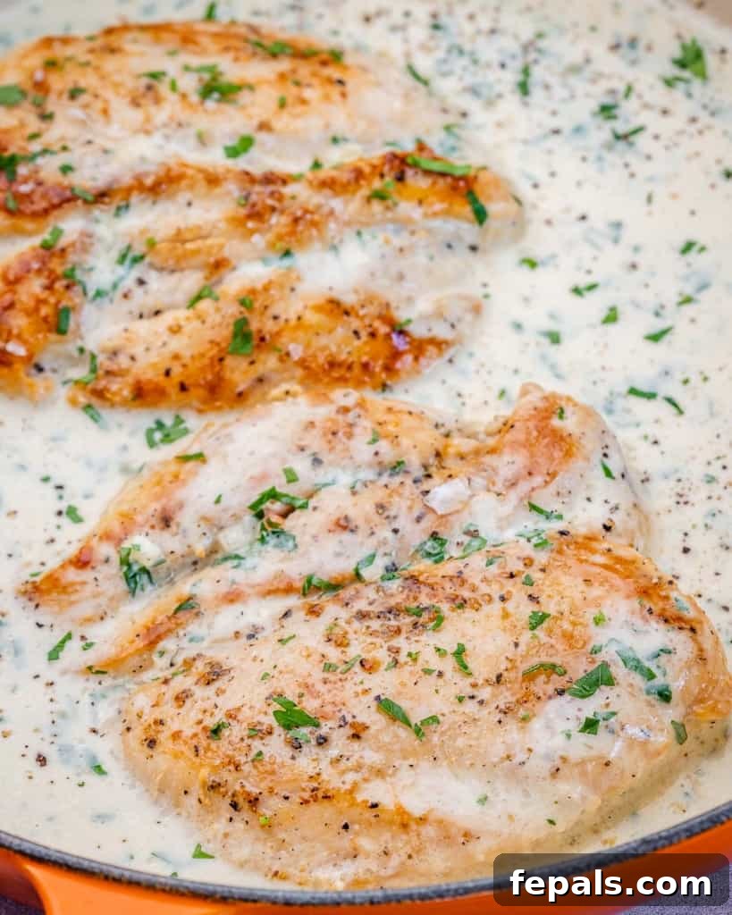 Ultimate Creamy Garlic Chicken Skillet 9 A close-up of chicken cooking in a rich, simmering cream-based sauce within a skillet, creating a luxurious and aromatic culinary scene.
