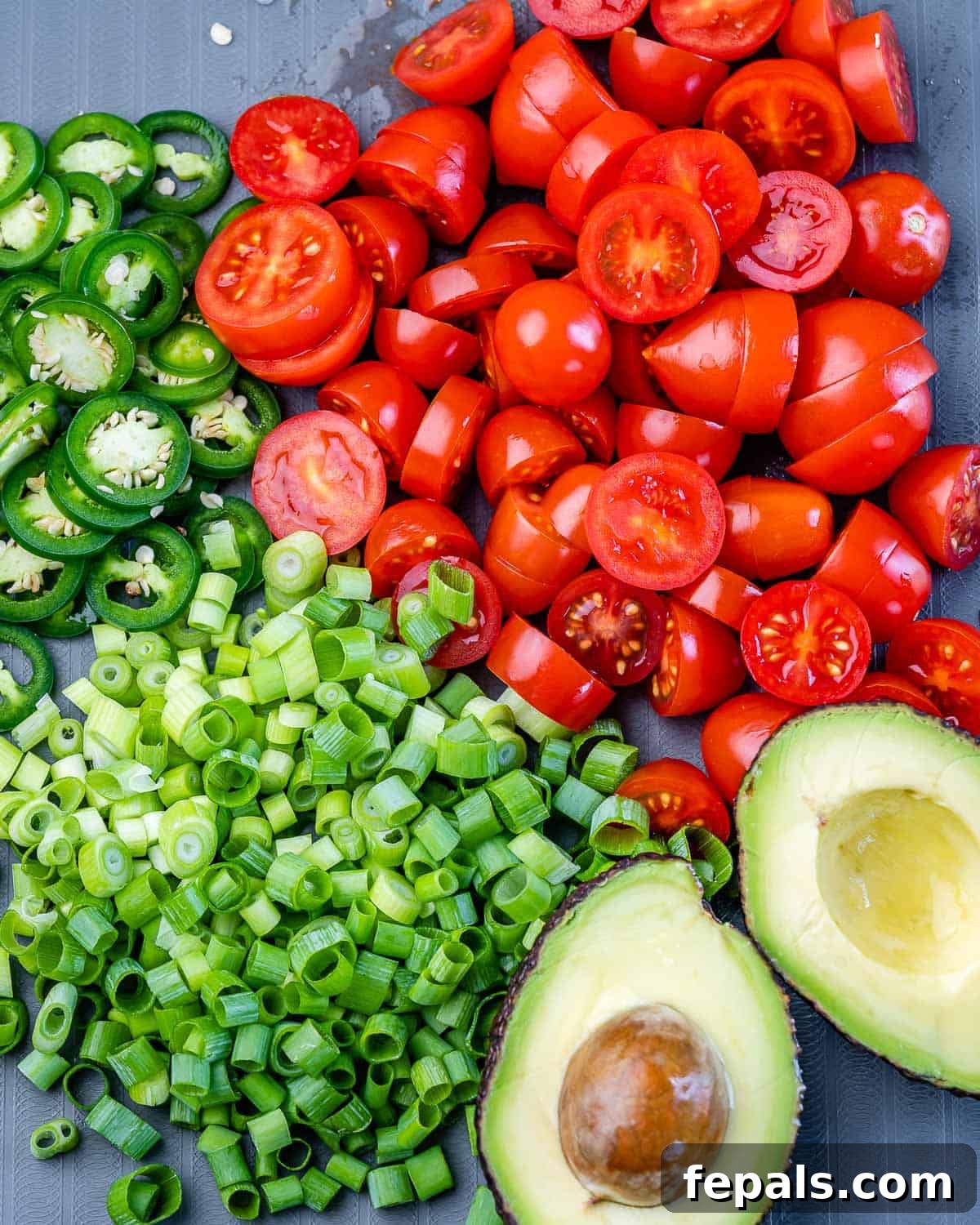 chopped green onions, tomatoes, jalapeño peppers, and avocado on cutting board