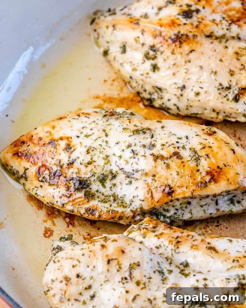 Chicken breast cooking and searing in a skillet.
