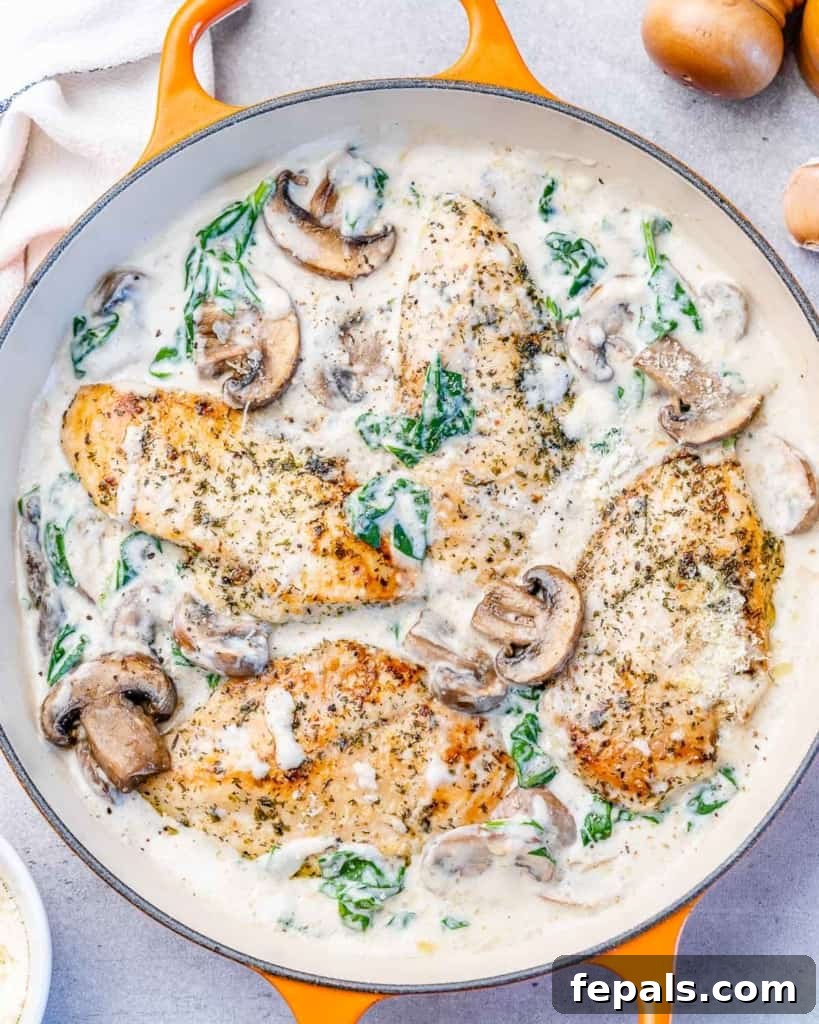 Creamy chicken with parmesan and spinach cooking in a skillet.