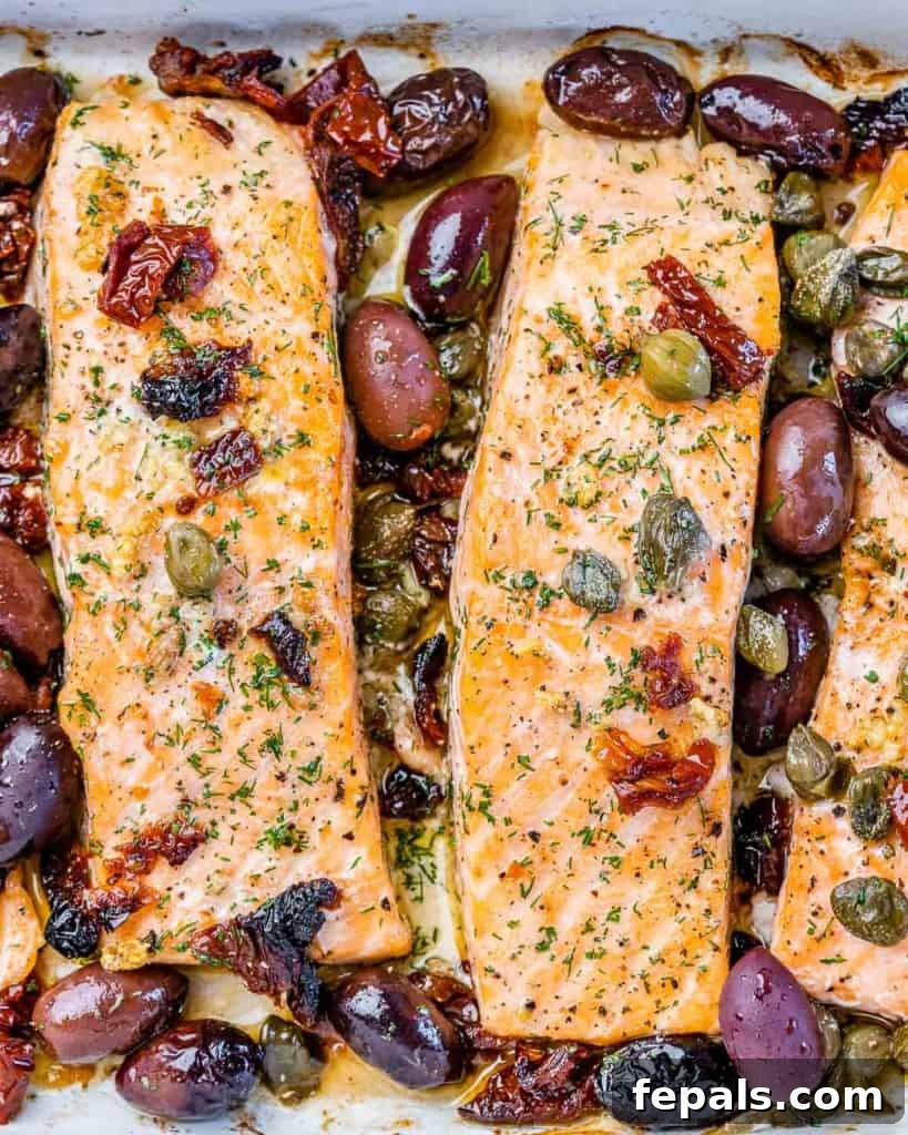 Pieces of salmon cooked with olives and capers in a white dish.
