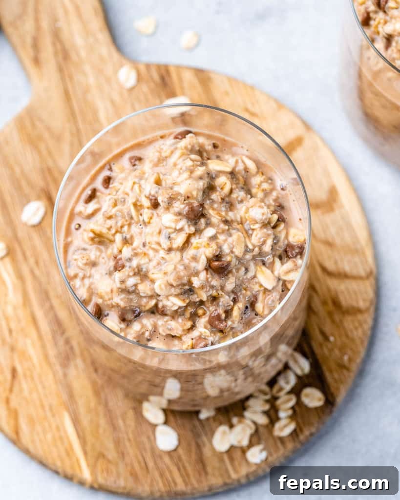 Guilt-Free Cookie Dough Oats 11 Üstten görünüşlü, garnitürlü ve kahvaltıya hazır bir kavanoz geceden kalma yulaf.