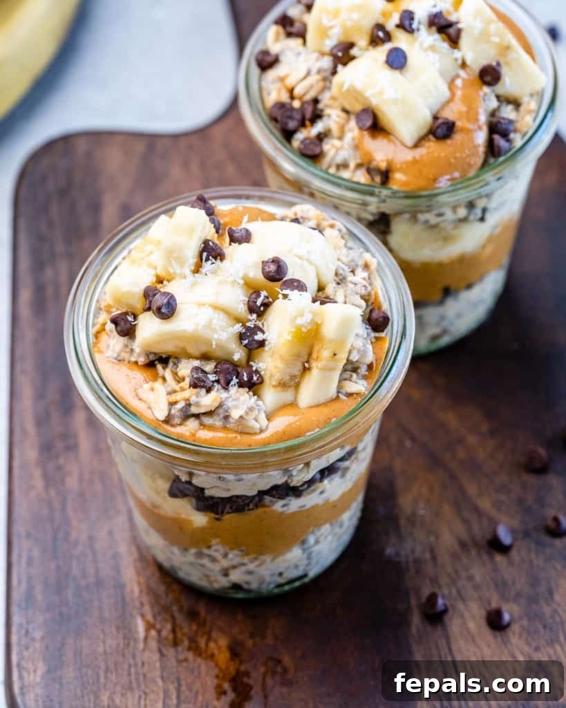 Top view of two jars of Chunky Monkey Overnight Oats on a wooden cutting board, garnished beautifully.
