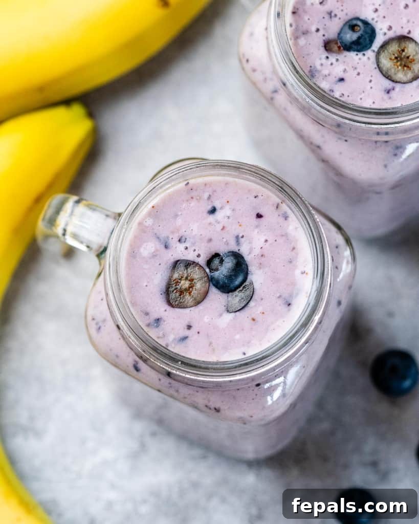 A close-up shot of a blueberry banana smoothie in a glass mason jar, showcasing its smooth, creamy texture and vibrant purple color, ready to be enjoyed.