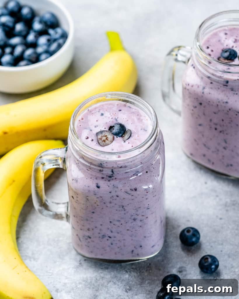 A vibrant blueberry banana shake in a tall glass jar, resting on a rustic wooden board, ready for a healthy and delicious sip.
