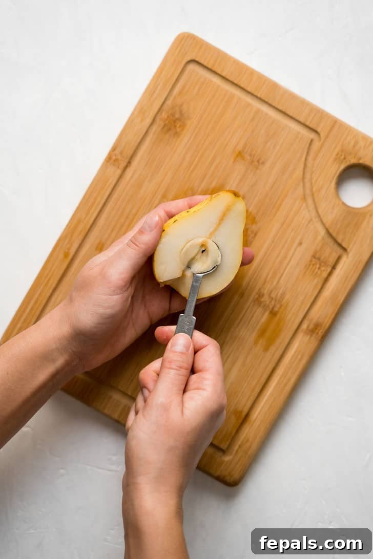 How to Cut and Eat a Pear A spoon efficiently scoops out the core and seeds from the center of a pear half.