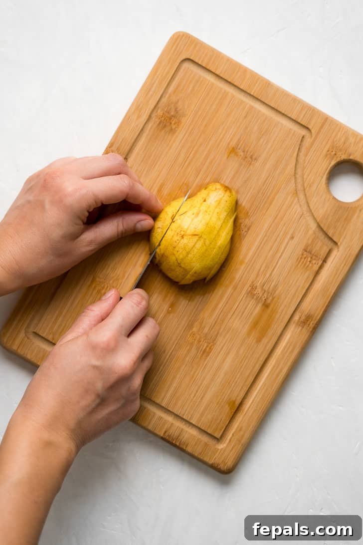 How to Cut a Pear Neatly arranged pear slices fan out across a rustic wooden board, showcasing their appealing texture.