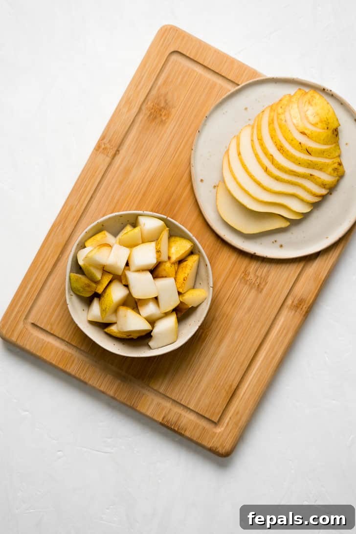 How to Cut a Pear Into Slices A beautifully composed shot featuring a bowl of pear cubes alongside a plate of pear slices, artfully arranged on a wooden cutting board.