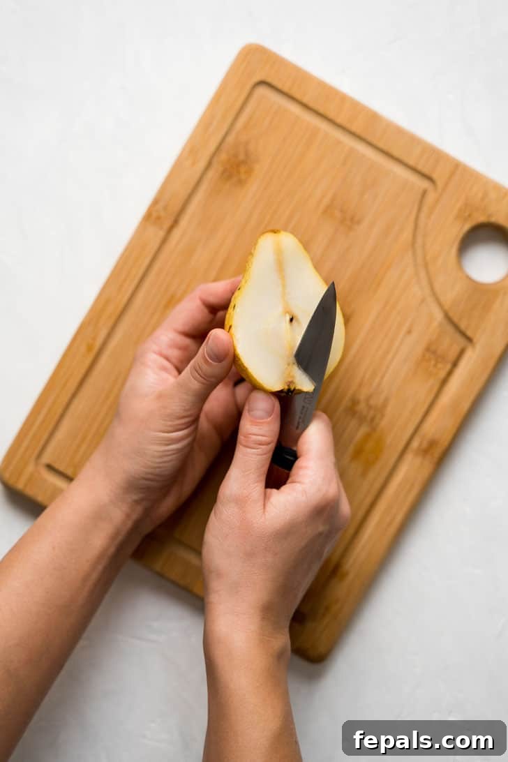 How to Cut a Pear A knife delicately removes the bottom portion of a pear half, preparing it for coring.
