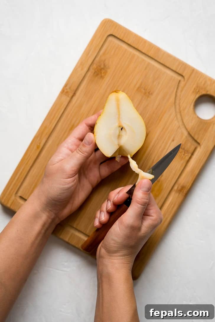 How to Cut a Pear Into Slices A hand gently pulls off the fibrous blossom end from the bottom of a pear half.