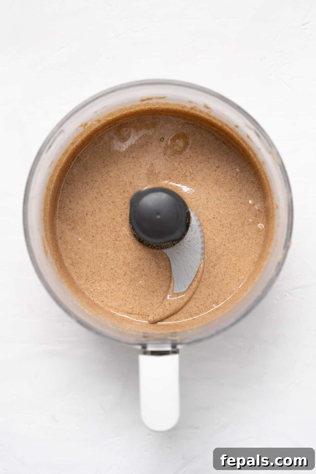 Smooth and creamy almond butter swirling in the food processor, signaling it's nearly done.