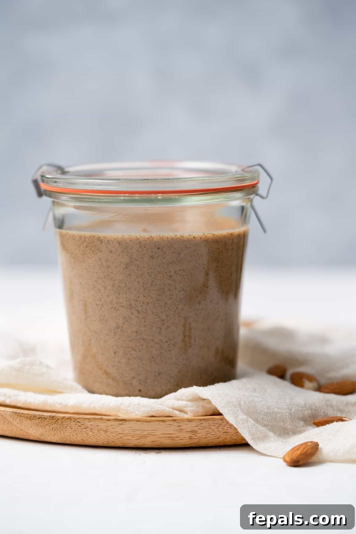Front view of a glass jar filled with creamy homemade almond butter, with its lid securely on.