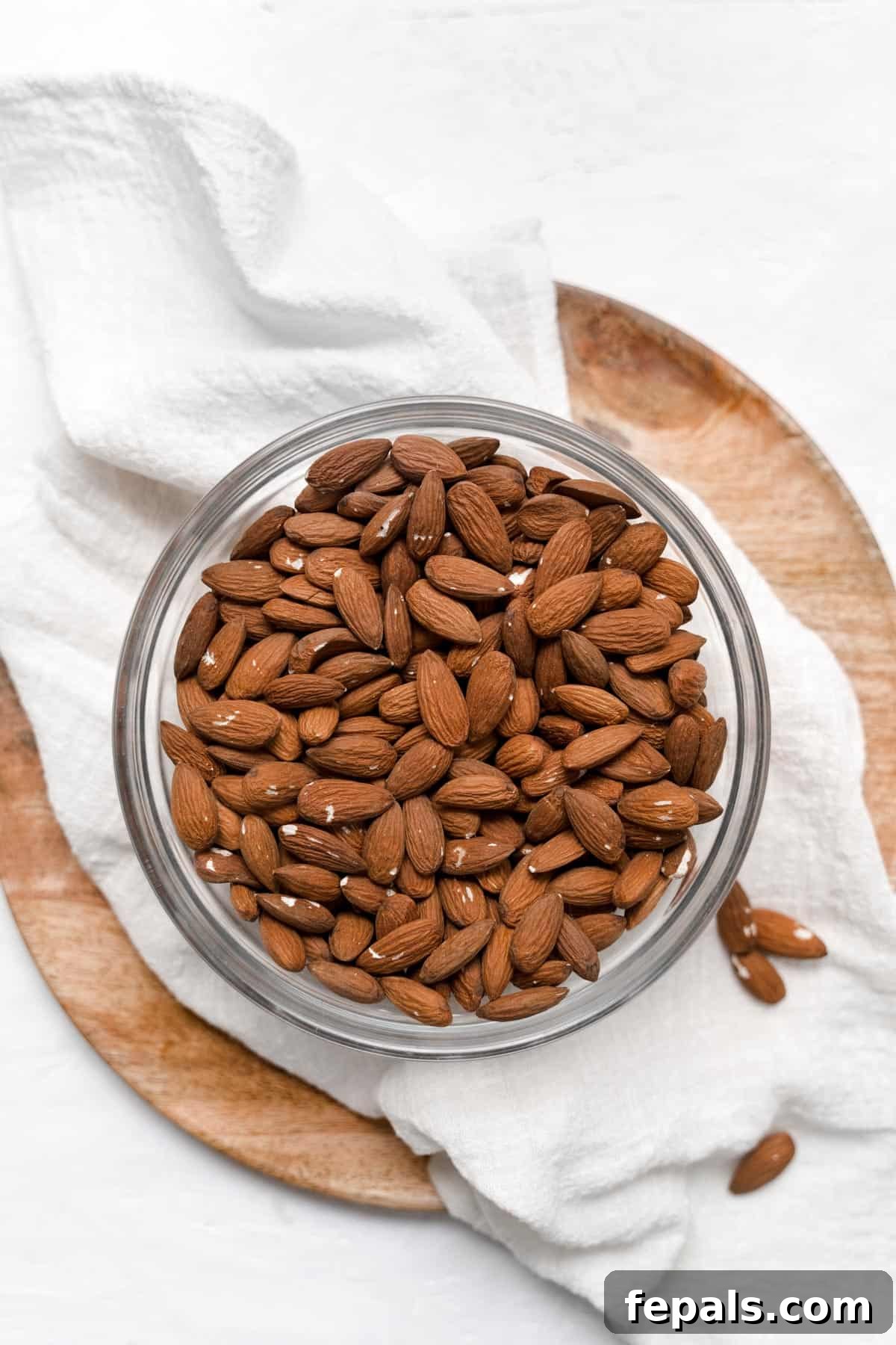 A bowl filled with whole, raw almonds, accompanied by a white linen napkin.