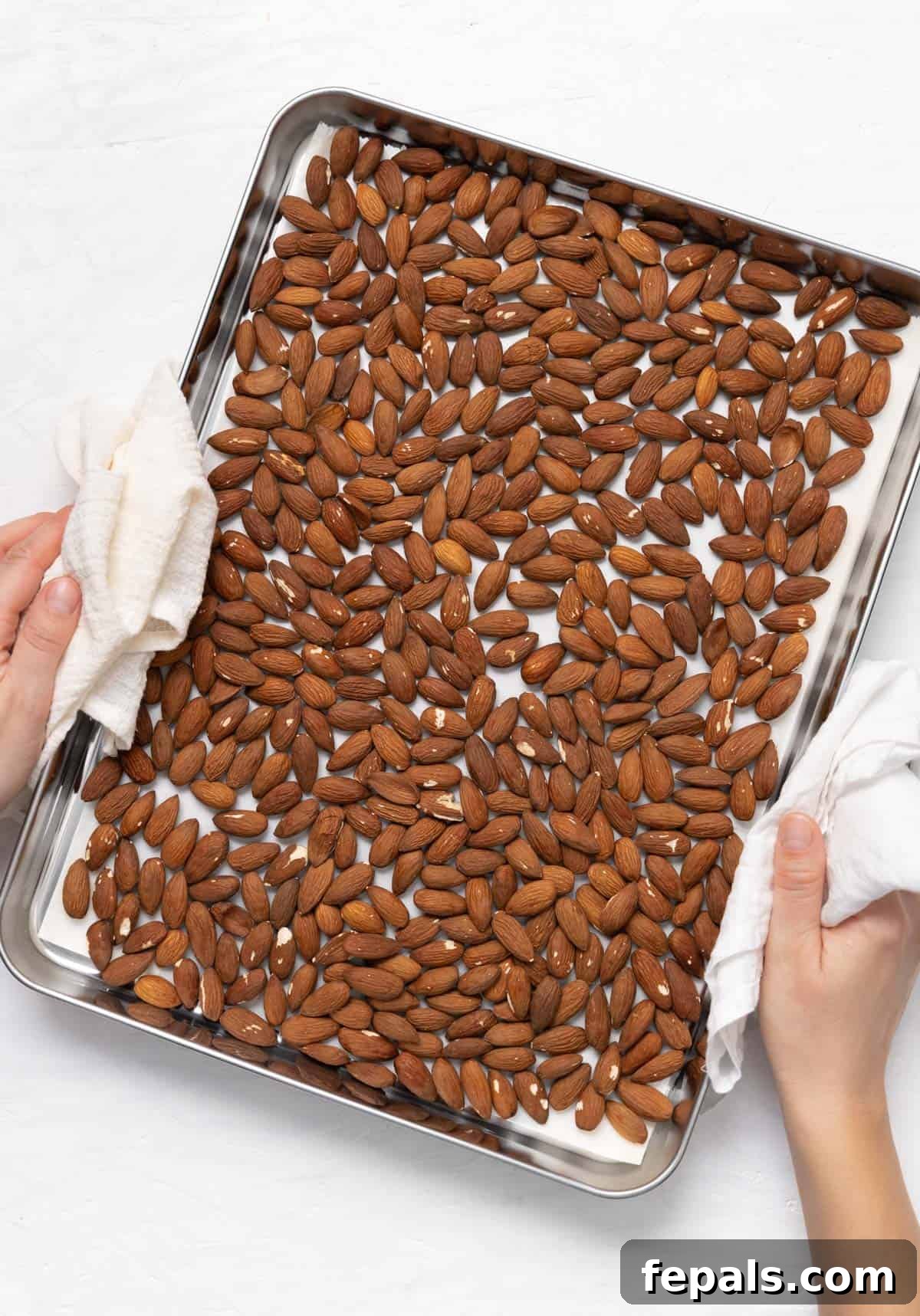 Close-up of raw almonds on a baking sheet, showcasing their readiness for the oven.