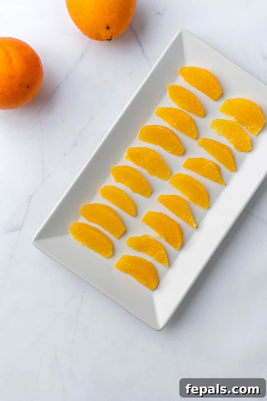 Delicious orange slices neatly arranged on a white plate, highlighting their vibrant color and fresh appearance.