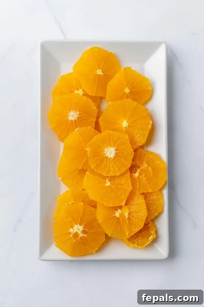 Perfectly cut orange slices beautifully arranged on a white plate, showcasing their vibrant color and juiciness.