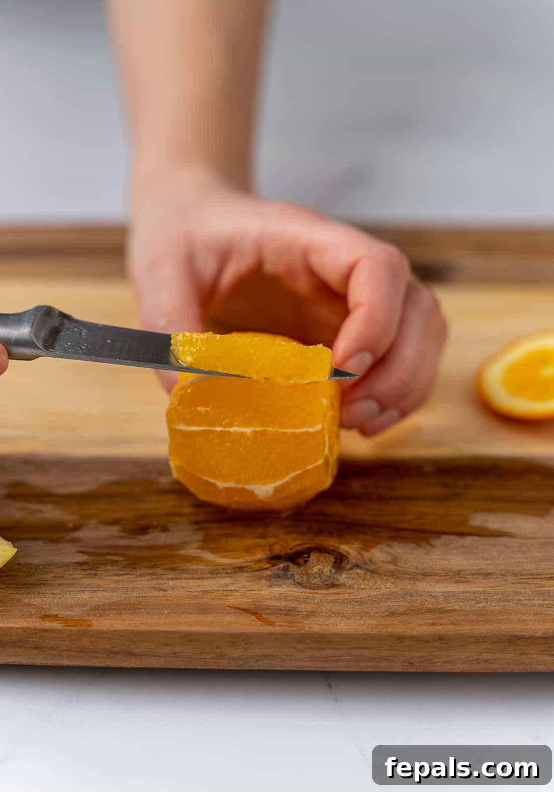 Another view of slicing an orange with a knife, highlighting the technique for separating juicy segments.
