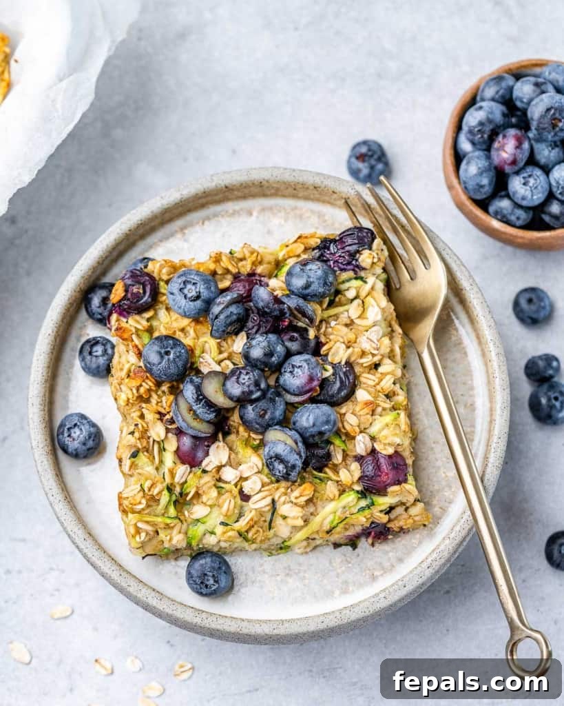 Serving of baked oatmeal made with zucchini and blueberries on a plate with a fork.