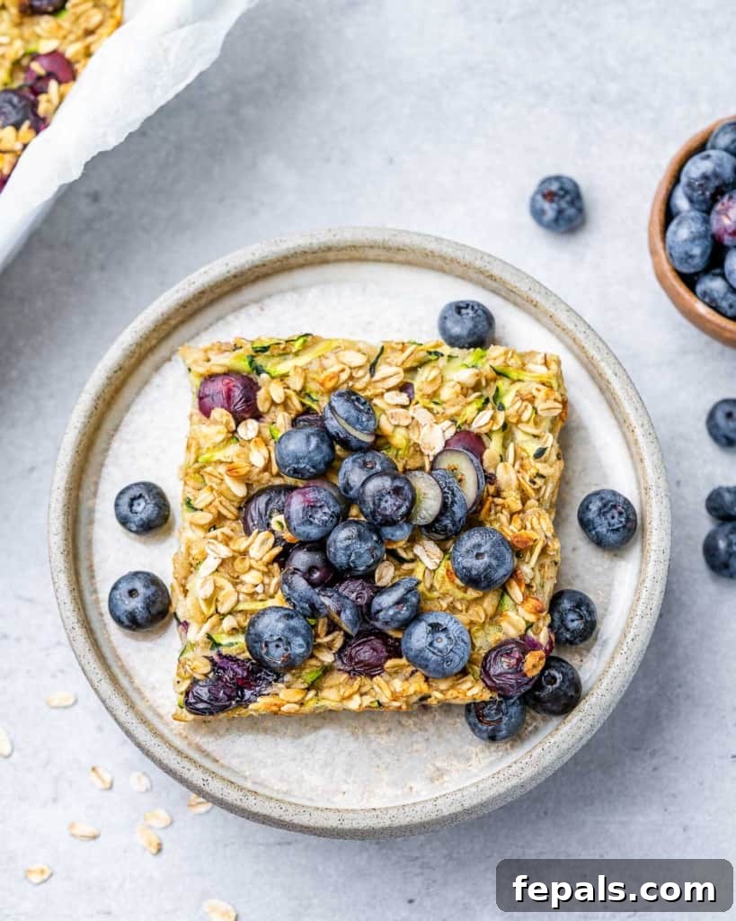 Square of blueberry baked oatmeal topped with fresh blueberries.