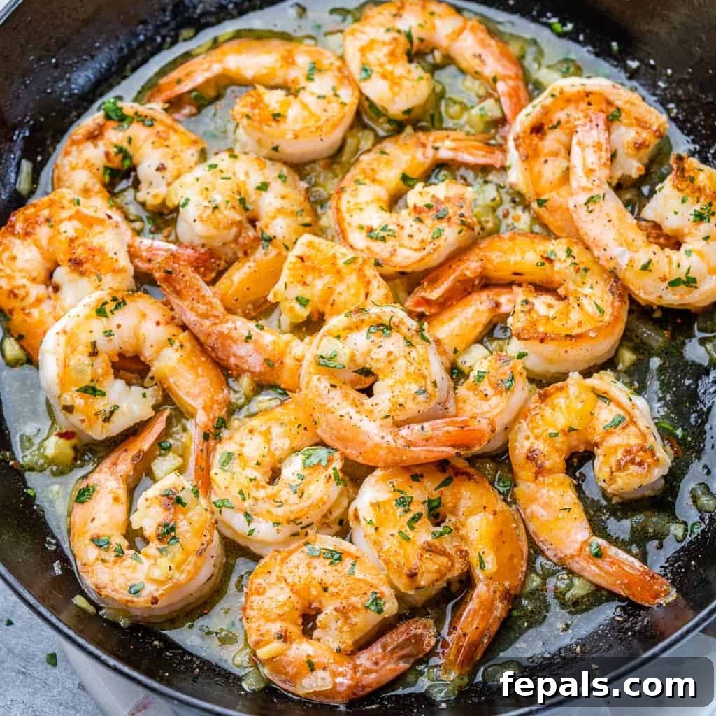 Guilt-Free Garlic Shrimp Scampi 2 top view of sauteed shrimp scampi in a skillet with parsley and lemon wedges