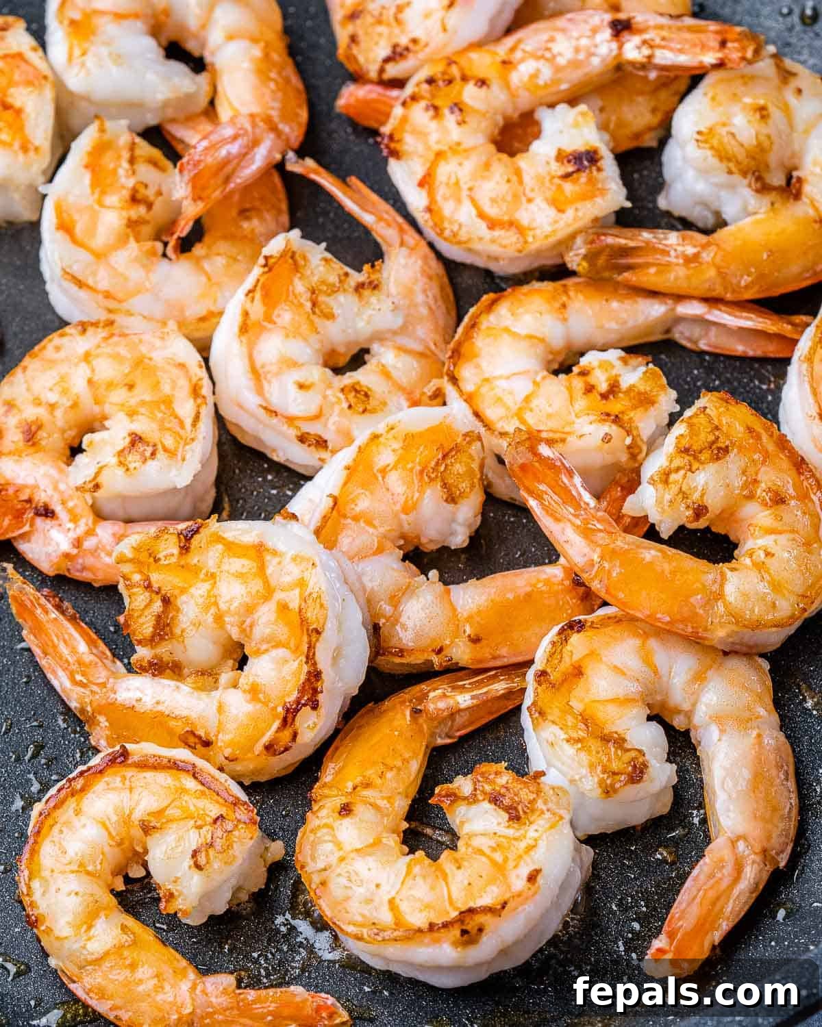Guilt-Free Garlic Shrimp Scampi 5 Large shrimp cooking in a skillet, turning pink
