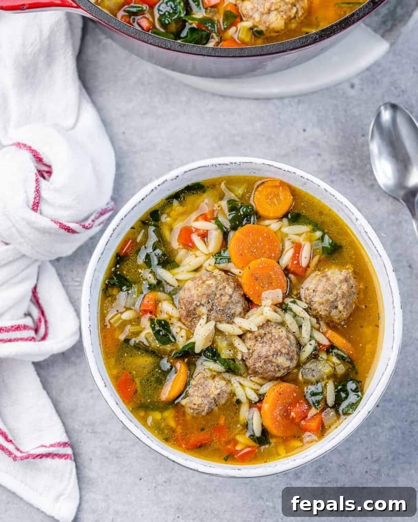 Nonna's Italian Wedding Soup 7 Soup made with meatballs, carrots and kale in a white bowl.