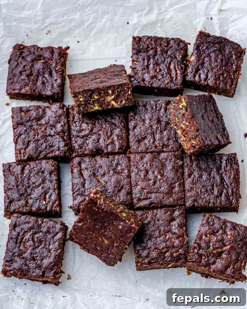 Top view of perfectly square, fudgy zucchini brownies arranged neatly on parchment paper, highlighting their rich chocolate color and moist texture.