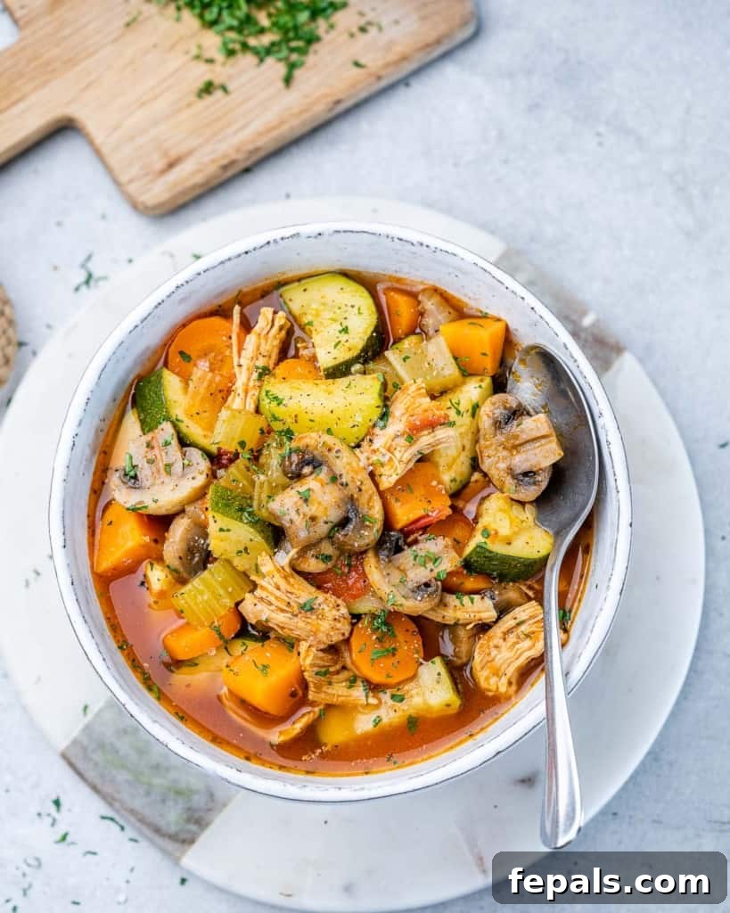 Hearty Chicken and Garden Vegetable Soup 6 Chicken vegetable soup served in a white bowl with a spoon, ready to eat.