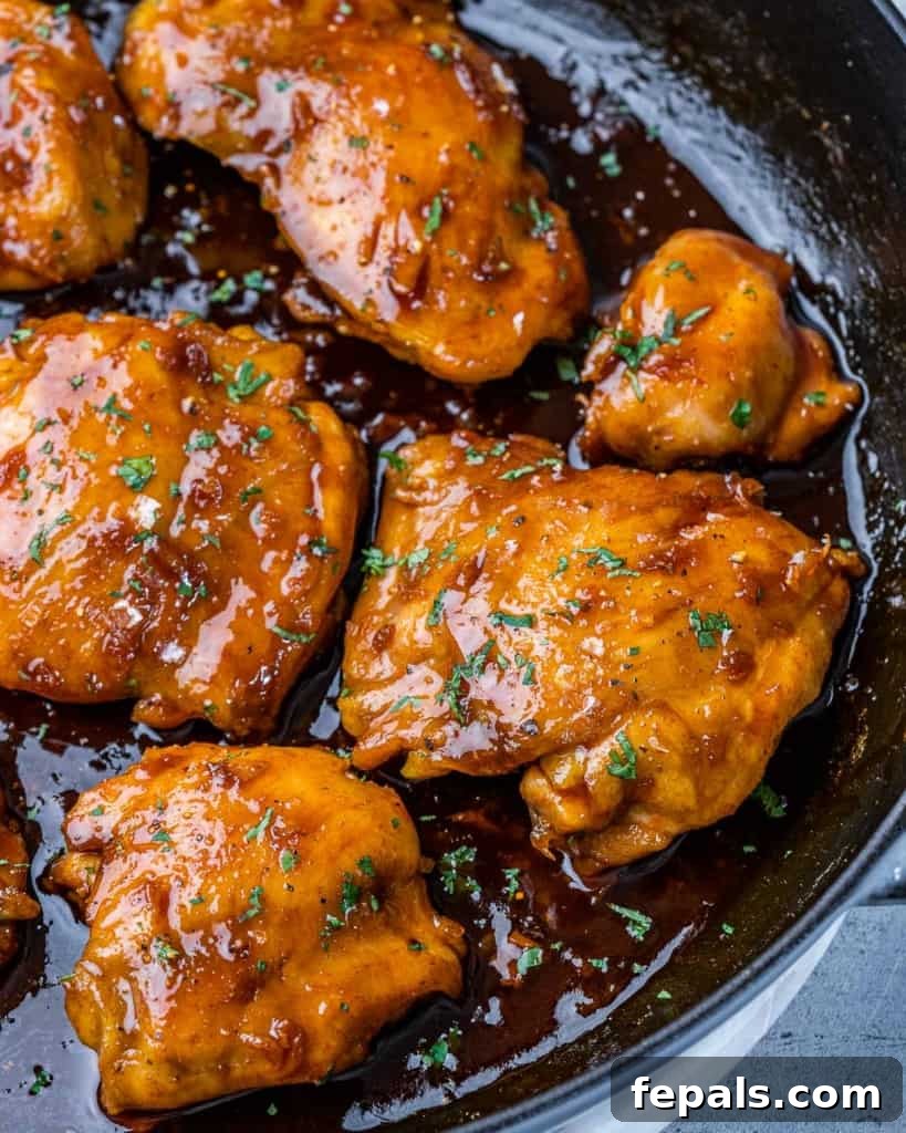 The Ultimate Chicken Adobo 7 Close-up view of perfectly seared chicken thighs in a black skillet, glistening with adobo sauce.