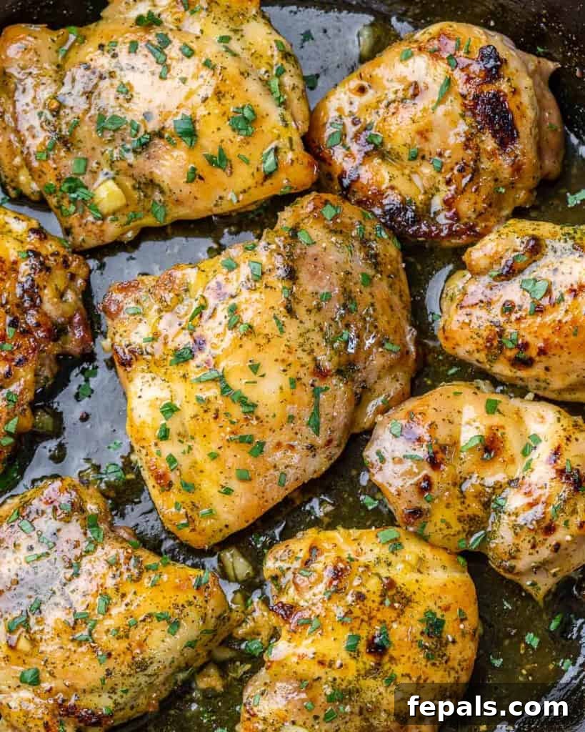 Effortless Baked Boneless Thighs 3 close up image of baked chicken thighs in a black skillet