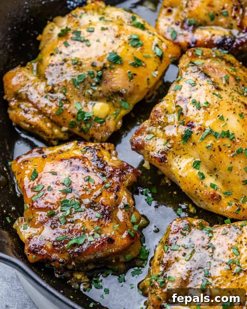 Effortless Baked Boneless Thighs 8 close up image of baked chicken thighs in a black skillet