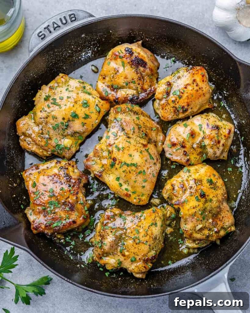 Effortless Baked Boneless Thighs 9 top view baked chicken thighs in a black skillet topped with freshly topped parsley